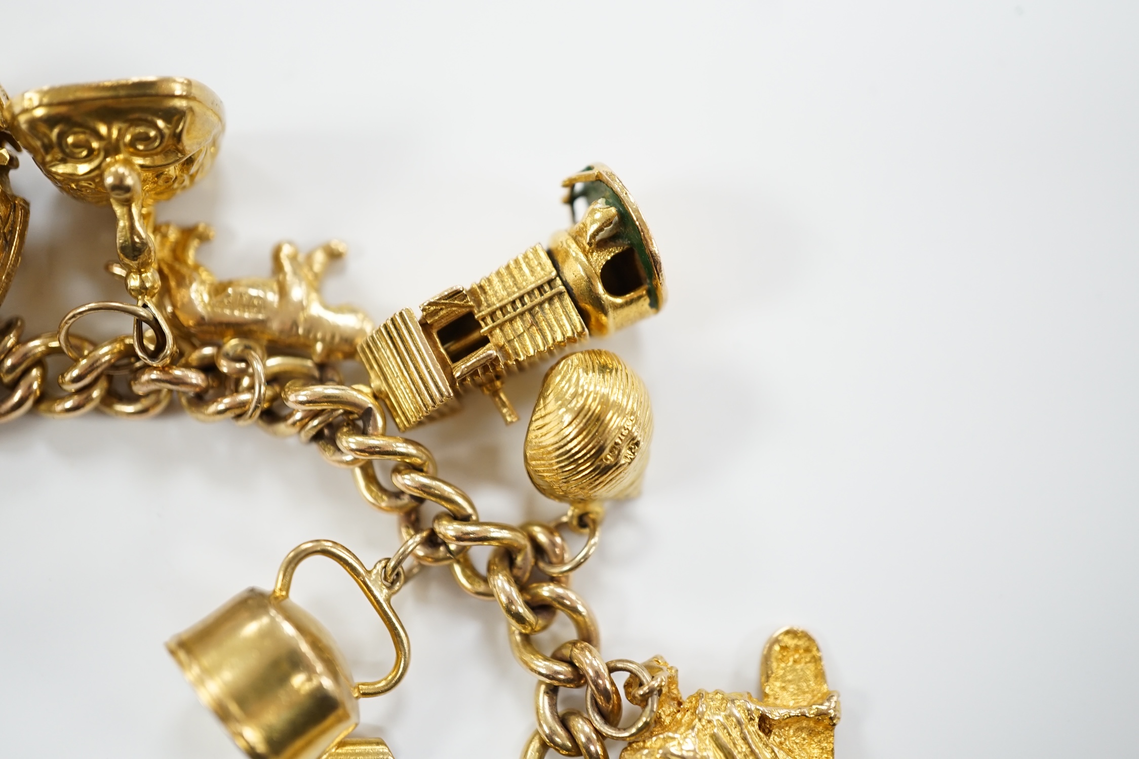 A 9ct gold curb link charm bracelet, with heart shaped padlock clasp and hung with assorted mainly 9ct gold charms
